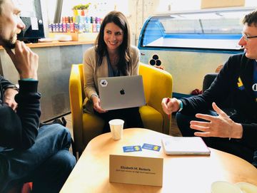 Three people having a discussion around a table in a casual setting.